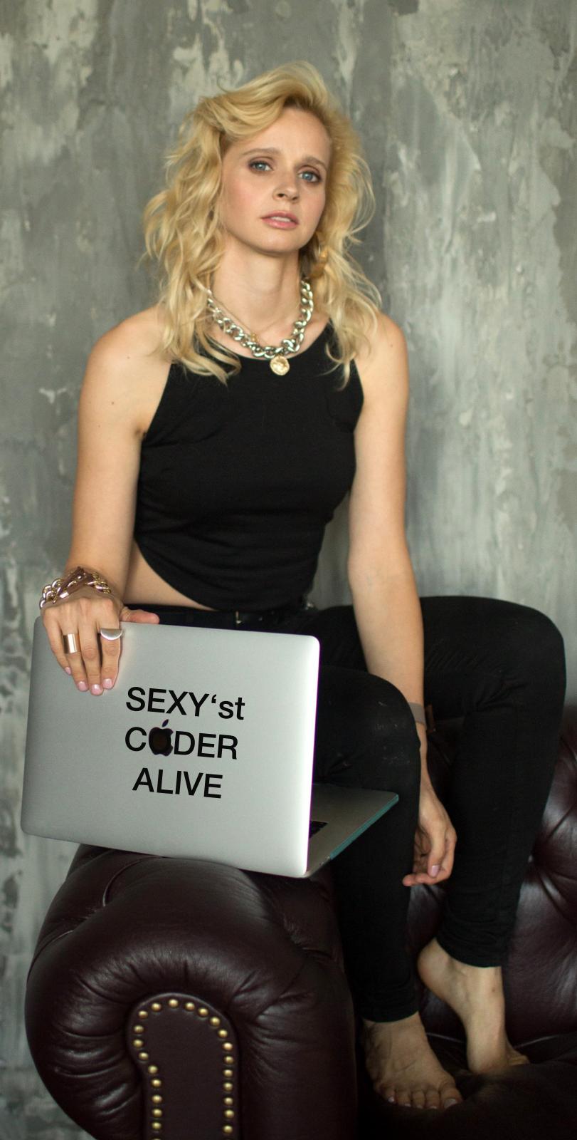 JaValiantsina — CyBERLINTINA, SEXY'st CODER ALIVE, sitzt mit MacBook auf Ledersessel